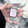 A hand holds a silver butterfly watch with a sparkling chain strap and a pink face displaying the time.