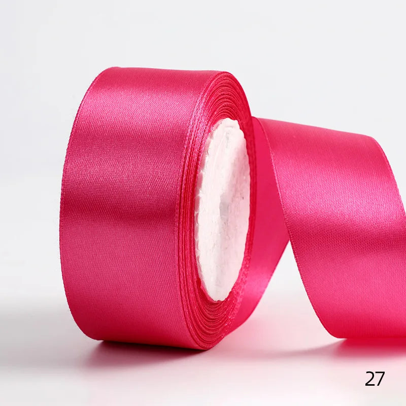 A roll of vibrant pink satin ribbon used for gift wrapping or DIY crafts.