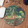A circular desk mat featuring a cute green frog surrounded by various potted plants and greenery.