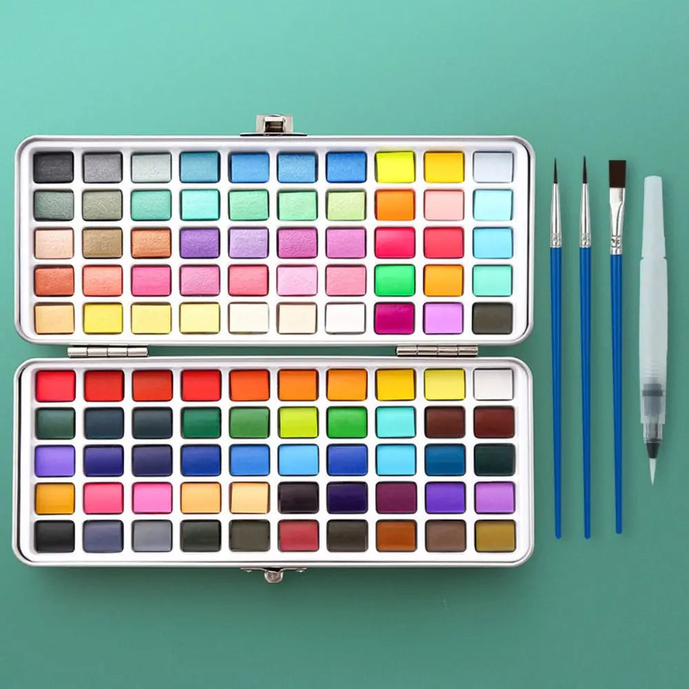A silver palette containing numerous watercolor paint pans and brushes.