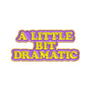 A sarcastic enamel pin featuring the text A LITTLE BIT DRAMATIC in yellow and purple lettering.