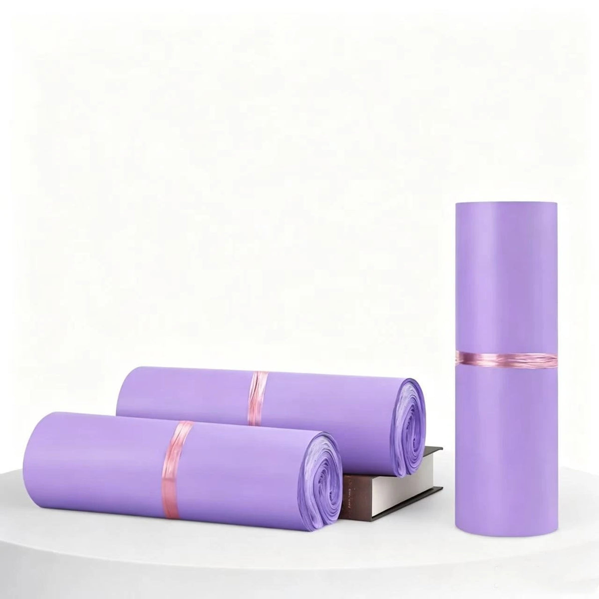 A roll of matte purple self-adhesive mailing bags is shown next to a tall cylindrical tube of the same color.