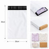 White self-adhesive courier mailer bags with a black plaid design and a purple garment inside.