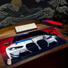 A large non-slip gaming mouse pad featuring a detailed racing car design on a wooden desk.