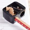 Afilador de lápiz automático negro con doble orificio, mostrando un lápiz de madera para afilar.