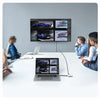 Three professionals collaborate around a table with a large monitor displaying car models and laptops.