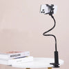 A black flexible gooseneck phone clamp mount positioned above a white table.