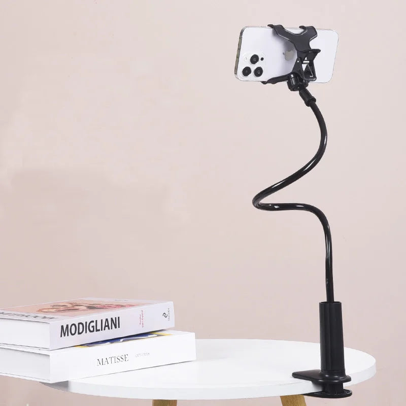 A black flexible gooseneck phone clamp mount positioned above a white table.