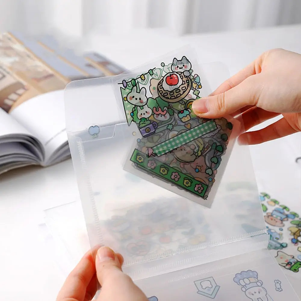 A hand holds a clear plastic storage book filled with various stickers and documents on a white surface.