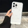 A clear silicone case with white bowknot decorations is shown on an iPhone, held by a hand.