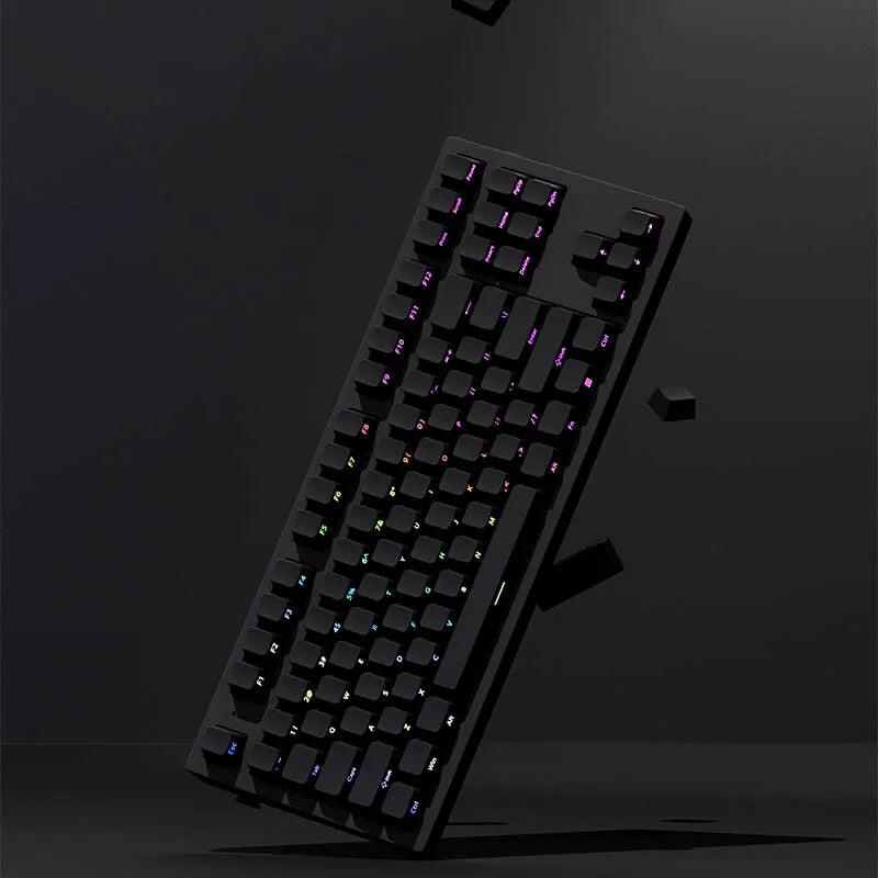 A close-up view of a black mechanical keyboard with purple and green PBT double-shot keycaps, shown at an angle against a dar