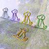 A collection of colorful, wire-like sitting dog paper clips in various shades of purple, yellow, and green arranged on a text