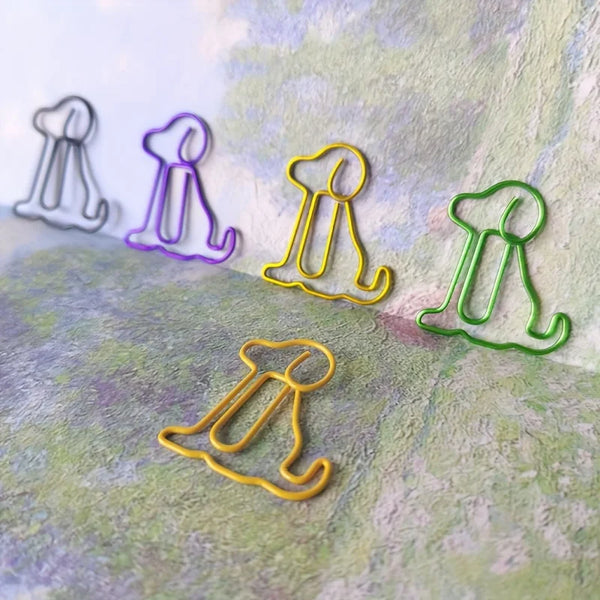 A collection of colorful, wire-like sitting dog paper clips in various shades of purple, yellow, and green arranged on a text