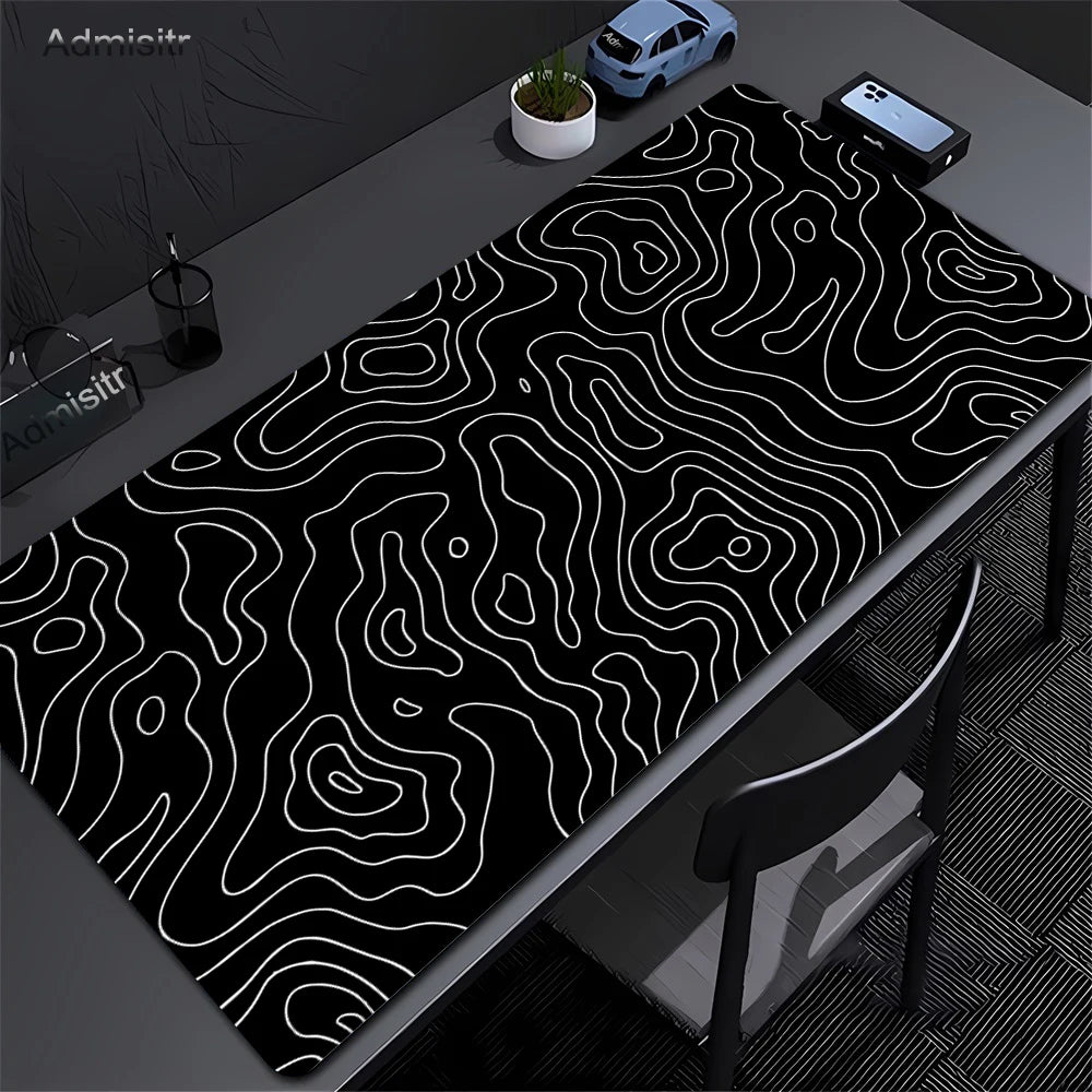 Extra large abstract desk mat with black and white wavy lines on a dark surface.