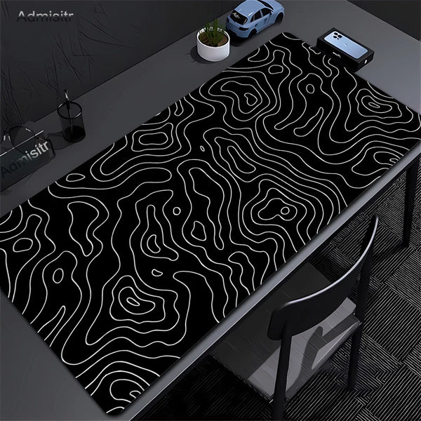 Extra large abstract desk mat with black and white wavy lines on a dark surface.