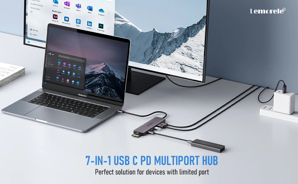 A silver laptop is connected to a 7-in-1 USB-C multiport hub on a desk with a monitor in the background.