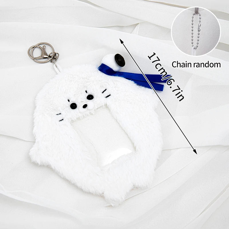 White plush animal photocard holder with a blue ribbon and a silver chain.