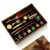 A luxury fountain pen set with various pens and a wax seal kit displayed in a wooden box.