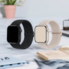 A black braided loop watch band and a beige braided loop watch band for Garmin devices are displayed on a white surface.