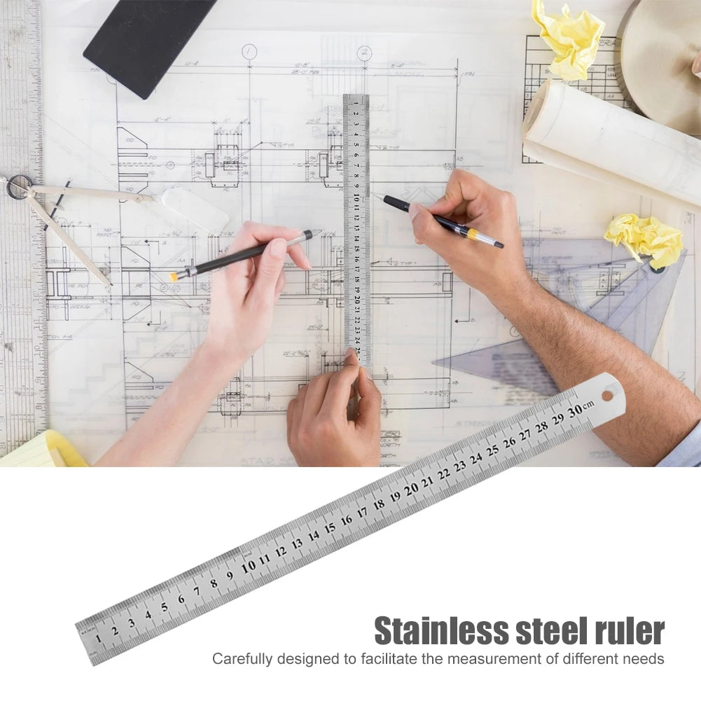 A stainless steel ruler is shown being used to measure on a blueprint or technical drawing.