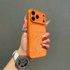 An orange phone case with a frosted velvet texture is held by a hand wearing a silver bracelet.