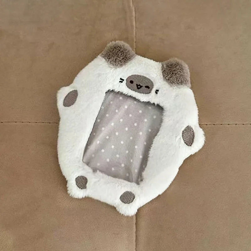 A white plush animal shaped like a bear with gray accents and a clear plastic cover for holding photocards.