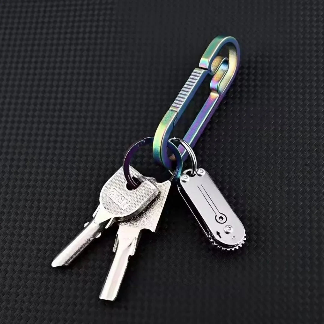 A compact stainless steel pocket knife attached to a keychain with a green and silver clasp.