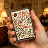 A hand holds a vintage stainless steel card and cash case featuring floral patterns.
