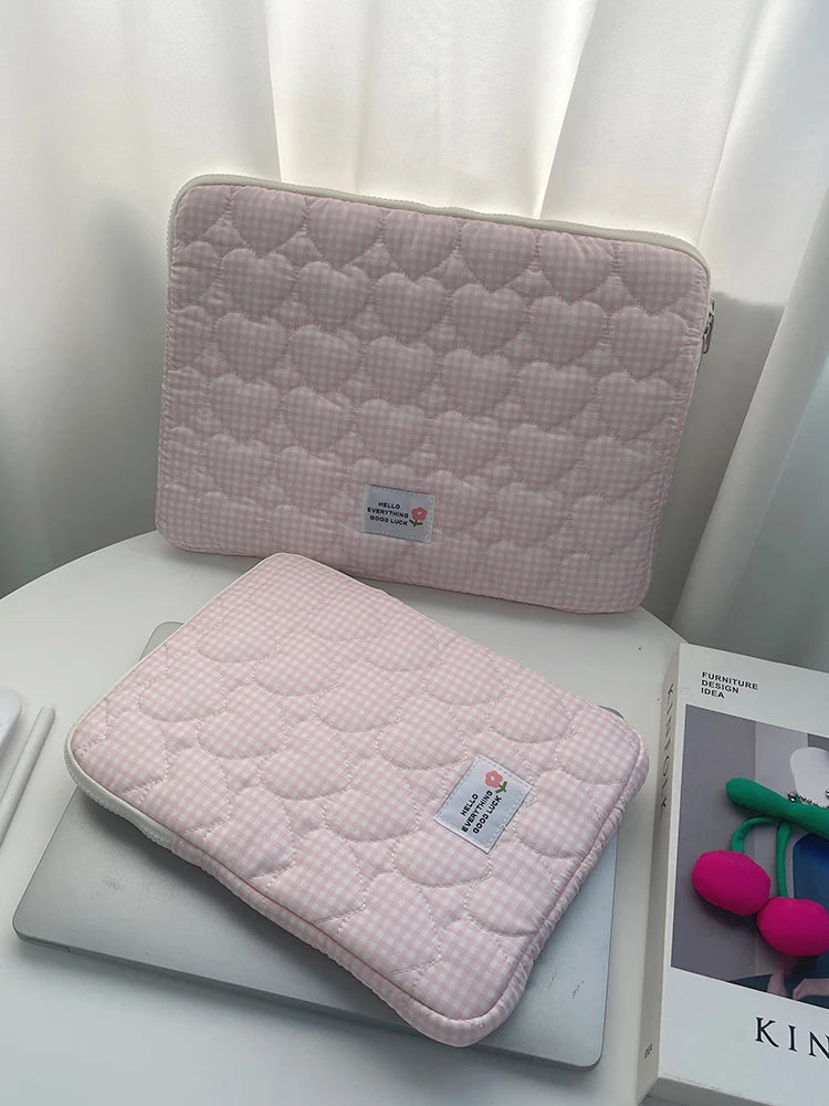 A pink quilted laptop sleeve is shown resting on a white surface.