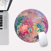 A pink disco ball shaped mouse pad with a non-slip rubber base is shown next to a laptop.