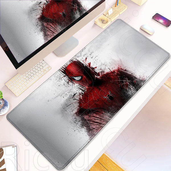 A black and red Spider-Man themed desk mat mouse pad is shown next to a laptop and a computer mouse.