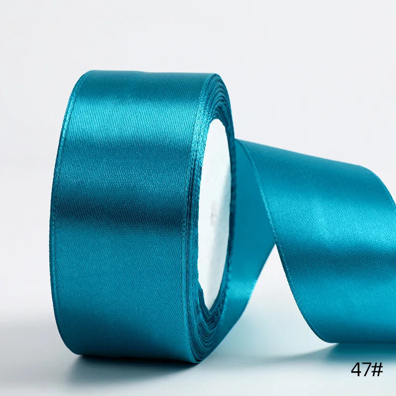 A roll of teal satin ribbon used for gift wrapping and DIY crafts.