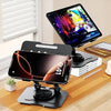 An adjustable dual rod tablet and phone stand holding a smartphone and a laptop on a wooden desk.
