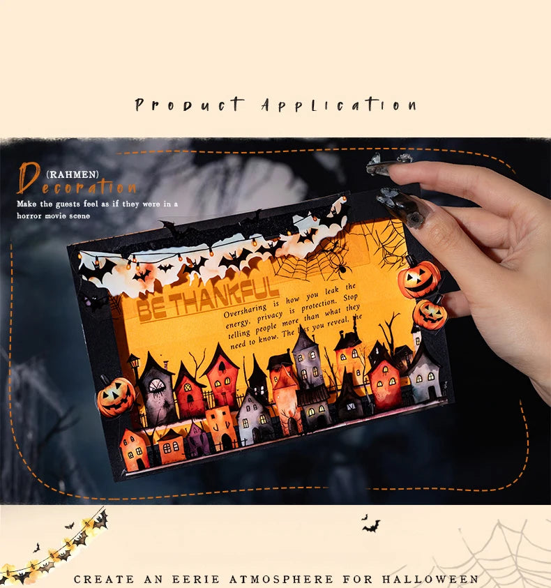A hand applies vintage gothic Halloween decorative masking tape featuring small houses and pumpkins onto a dark surface.