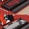 A close-up view of a black mechanical keyboard with red PBT sublimated shark keycaps and a matching keyboard wrist rest on a 