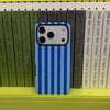 A blue and white striped phone case for an iPhone is displayed in front of a shelf of books.