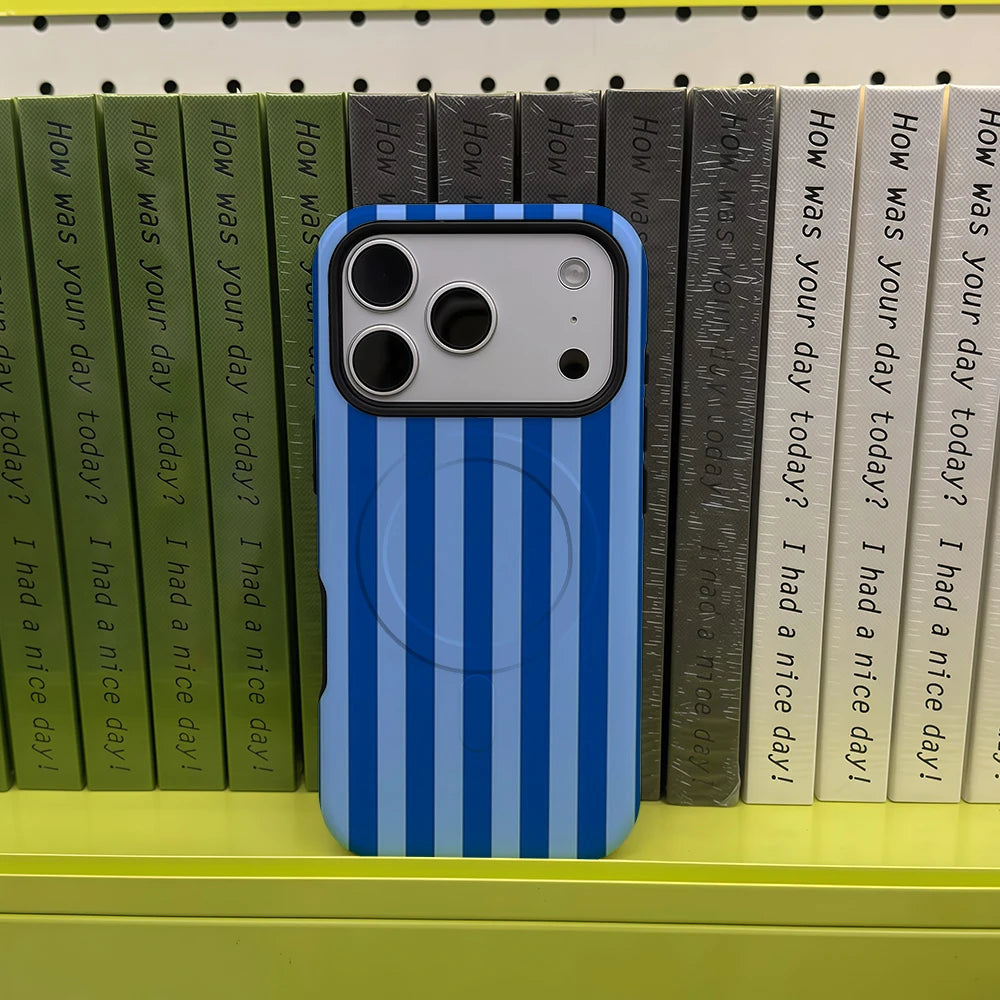 A blue and white striped phone case for an iPhone is displayed in front of a shelf of books.