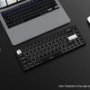 A close-up view of a laptop, keyboard, and mouse on a dark surface with PBT keycaps visible.