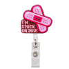 A pink, heart-shaped badge reel holder with a red glitter background and a pink medical symbol design.