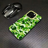 A green and camouflage patterned phone case lying next to a silver Apple AirPods case on a dark surface.