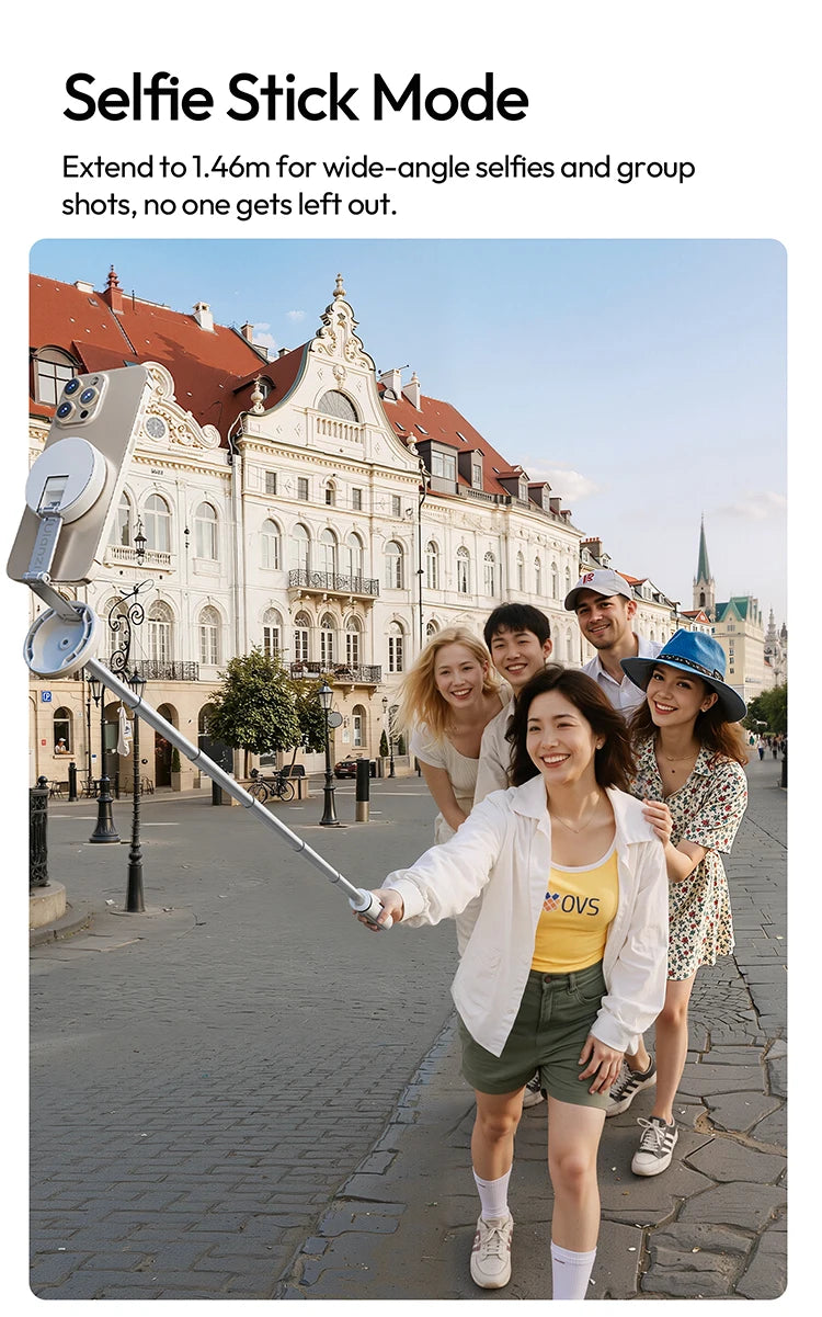 A woman uses a selfie stick to take a wide-angle photo of herself and a friend in a European city street.