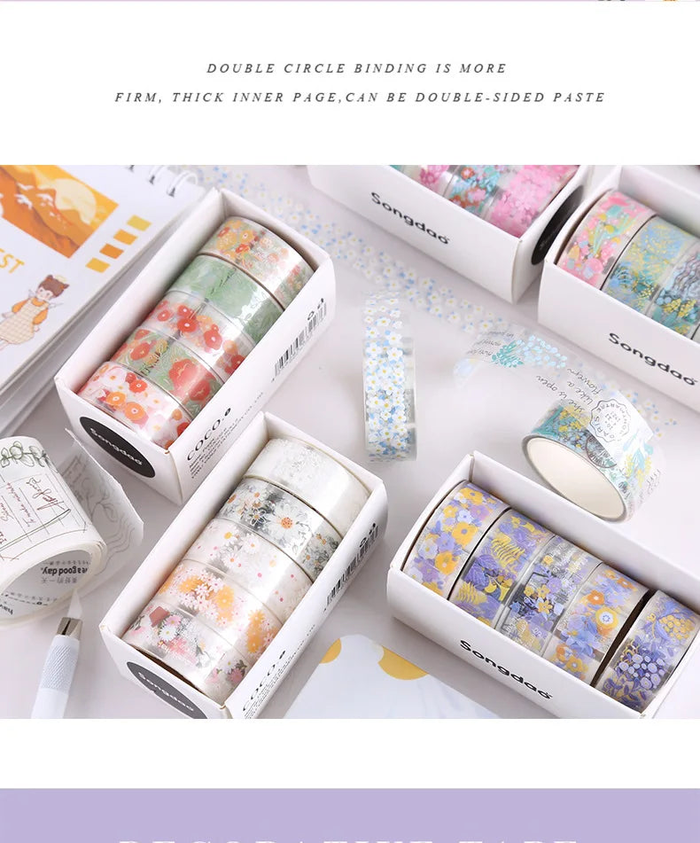 A set of colorful decorative transparent washi tape rolls in various shades and patterns displayed in open boxes.