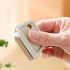A hand holds a white mini ceramic box cutter with an auto-retractable blade.