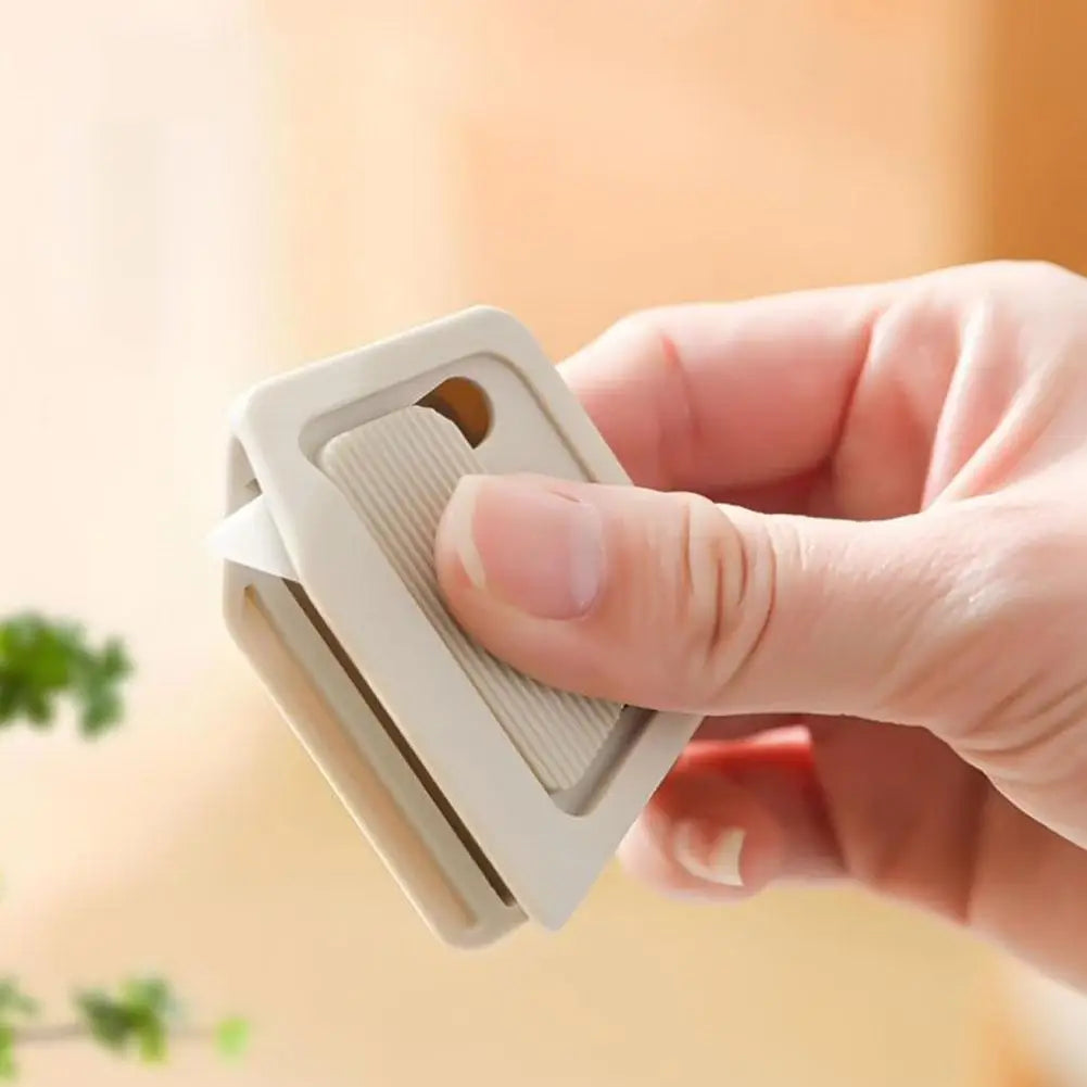 A hand holds a white mini ceramic box cutter with an auto-retractable blade.