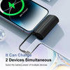 A black power bank is shown charging a smartphone, illustrating its ability to charge two devices simultaneously.