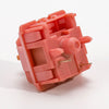 A close-up view of a pink rosewood linear mechanical keyboard switch housing.