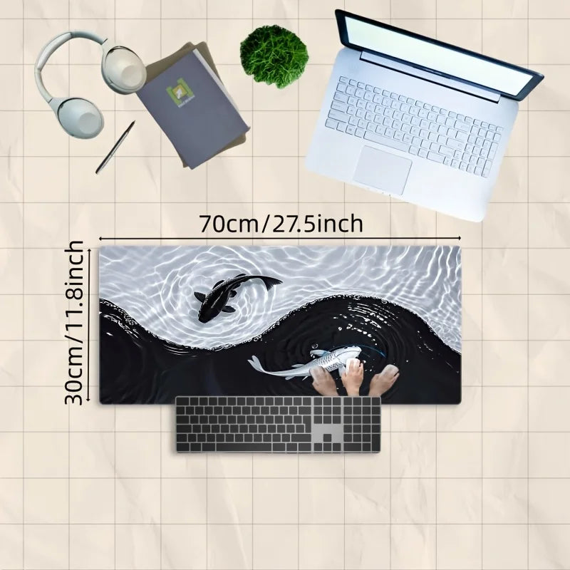 A gaming mouse pad featuring a black and white koi fish pattern, shown next to a laptop and headphones.