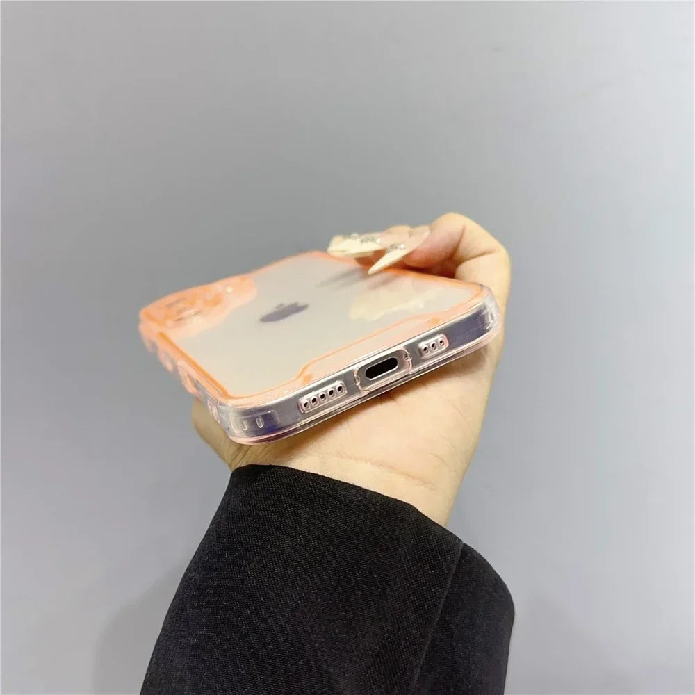 A hand holds a clear phone case with an orange tint for iPhone protection against a plain gray background.