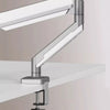 A silver adjustable desk monitor arm extending over a white desk surface.