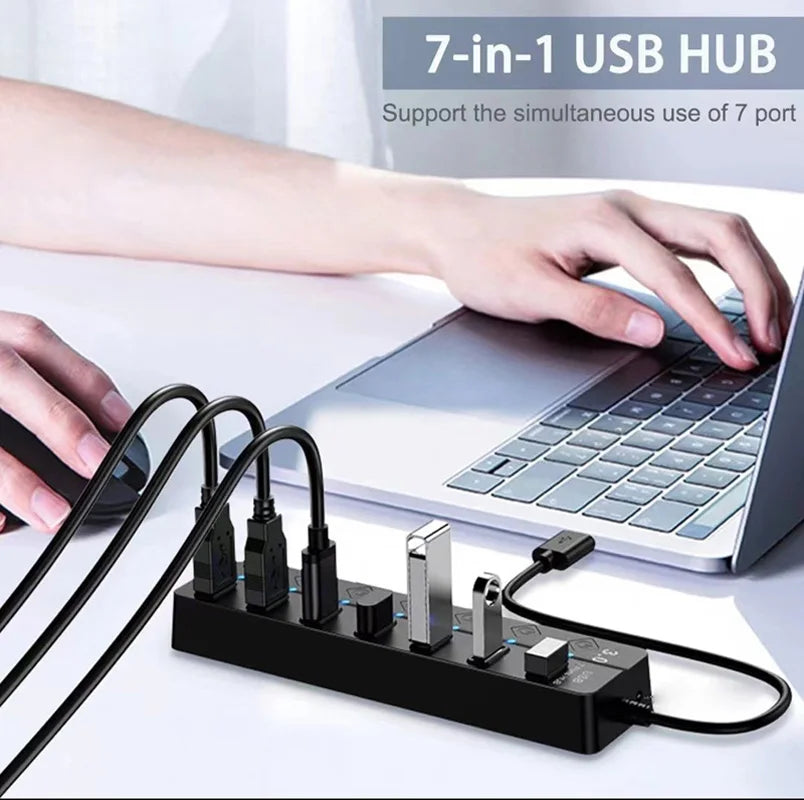 موزع USB أسود من 7 في 1 مع منافذ متعددة ومؤشر LED بجوار حاسوب محمول.